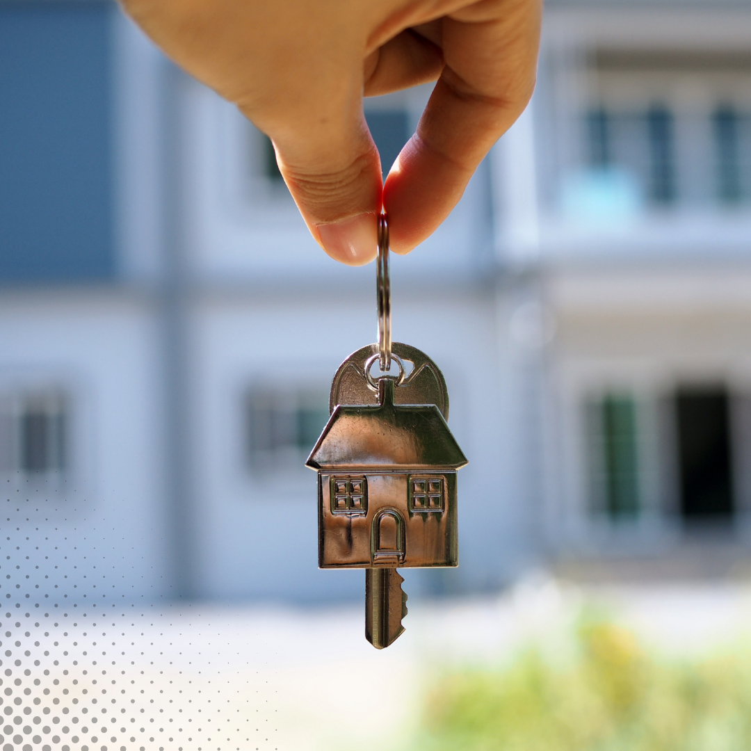A hand clutching a house-shaped keychain and a key