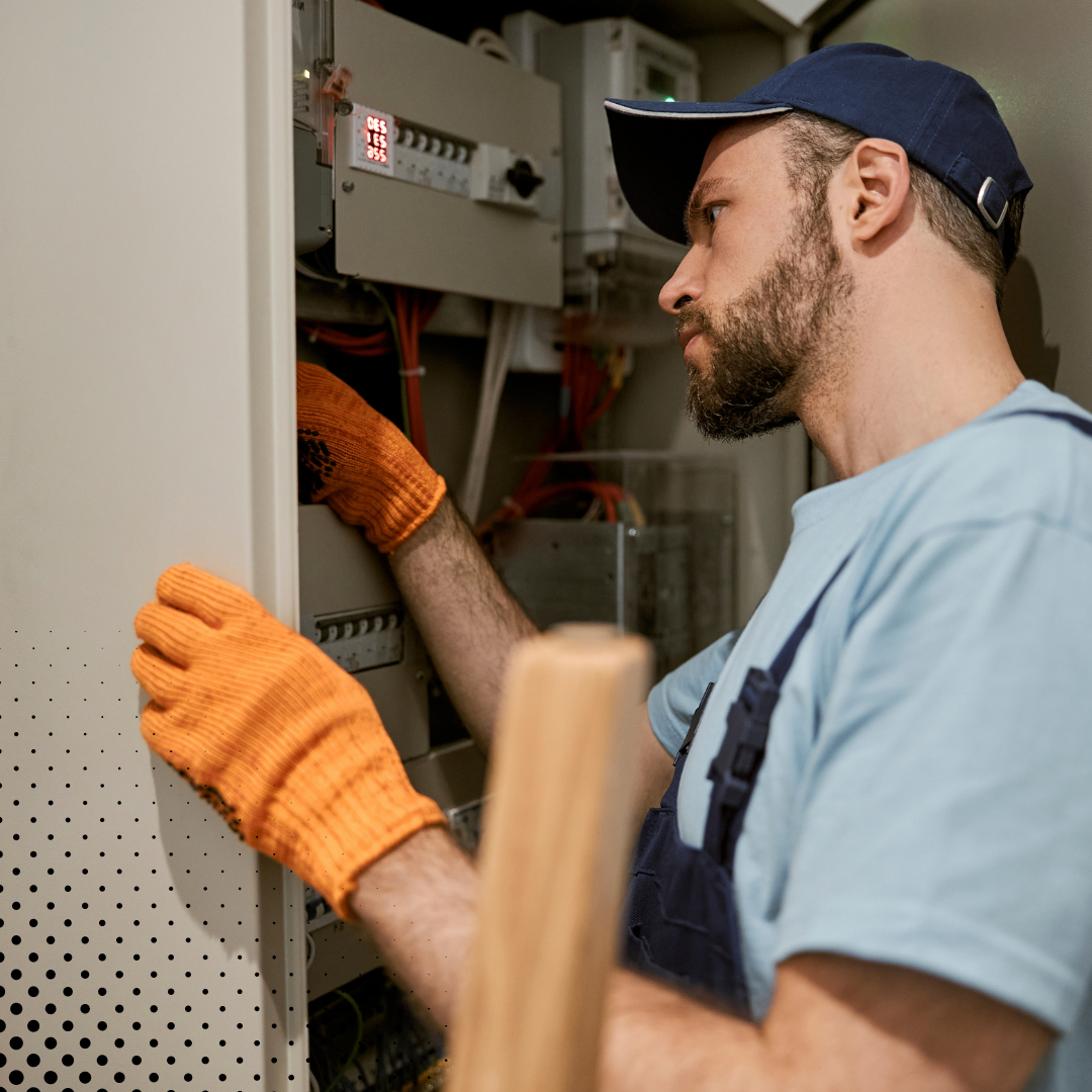 With a focused expression, the home inspector in a blue cap and orange gloves checks the components of an electrical panel.