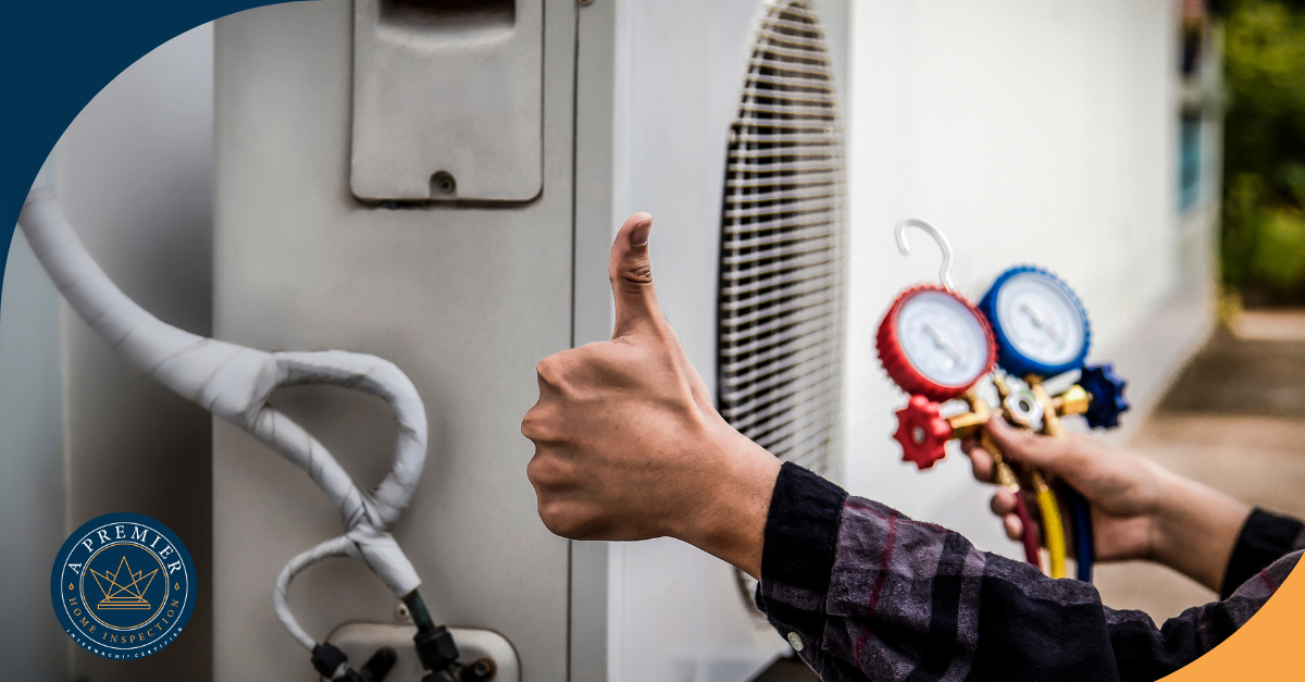 Technician giving a thumbs-up while holding HVAC pressure gauges near an outdoor air conditioning unit.
