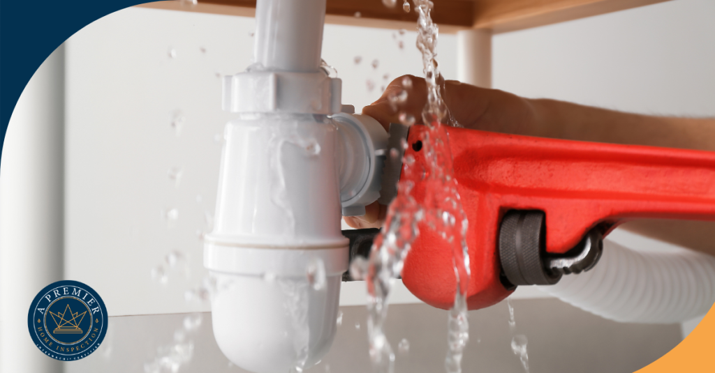 Plumber fixing leaking pipe under sink with a wrench.