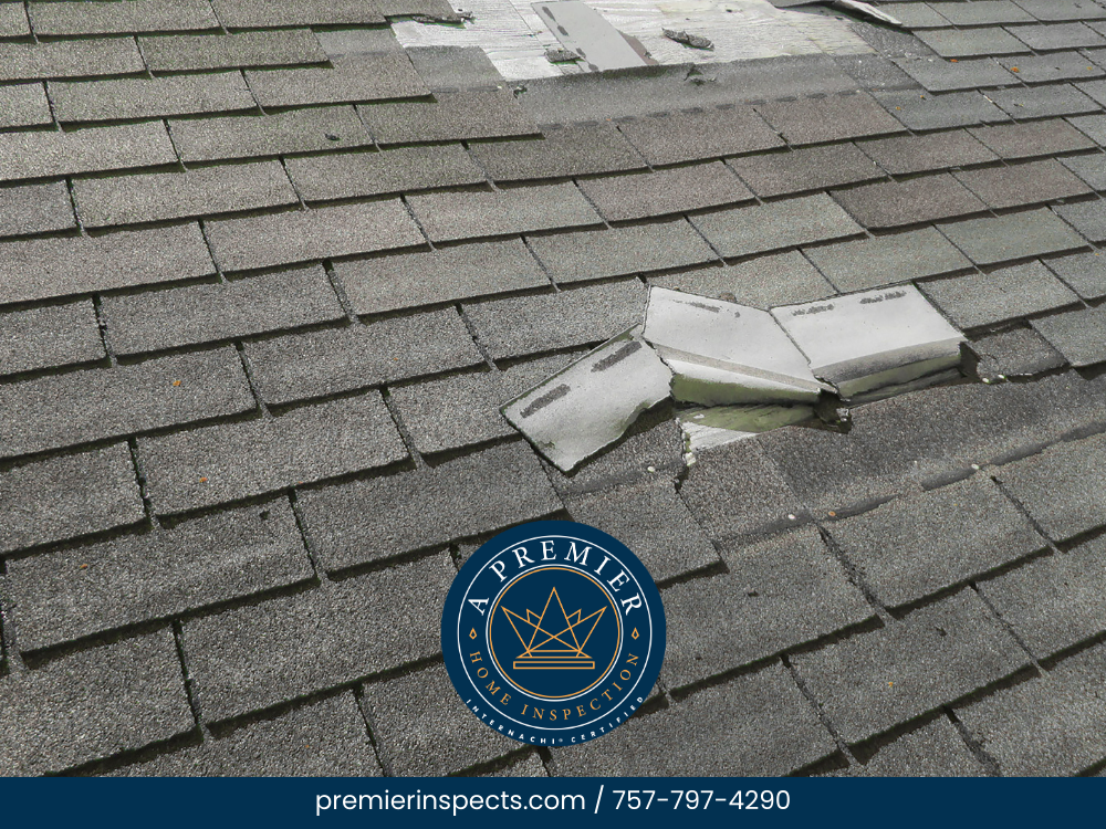 Damaged roof shingles with exposed flashing indicating potential leak risk.