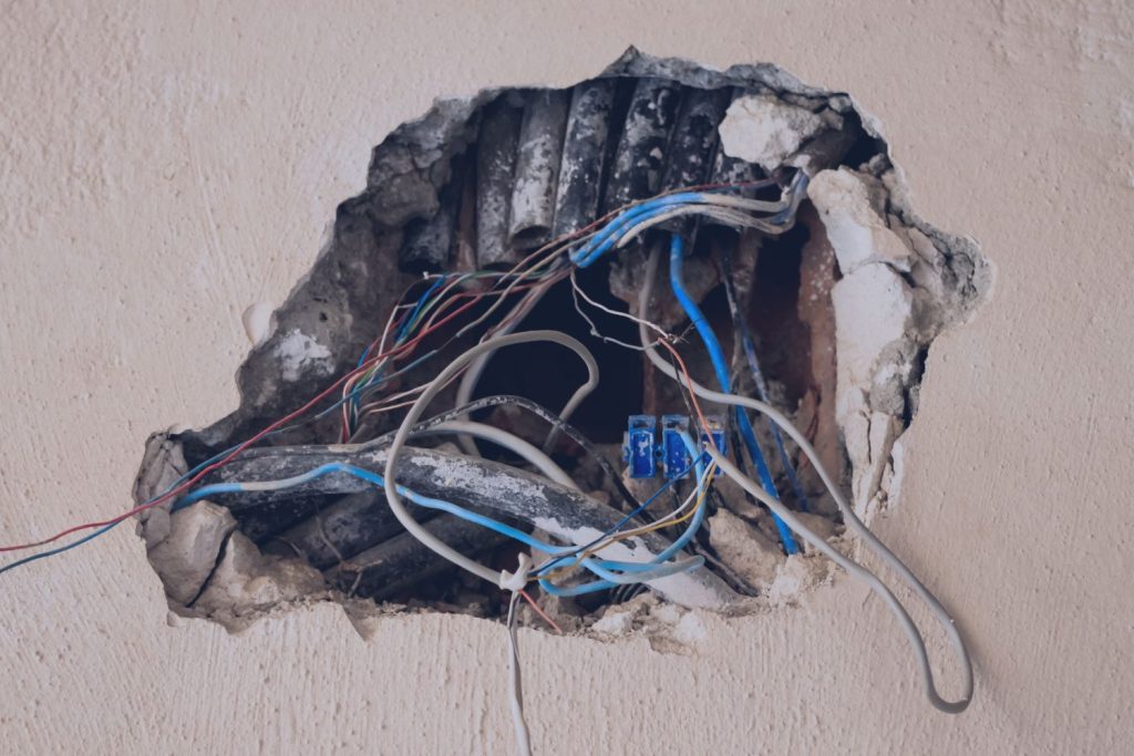 Wiring exposed behind a wall during a home inspection, showing discoloration consistent with corrosion
