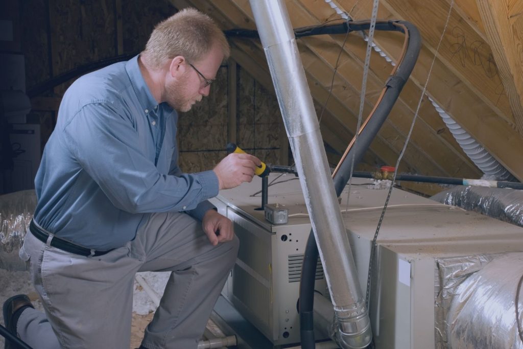 Home inspector examining HVAC system in an attic for signs of Chinese drywall corrosion